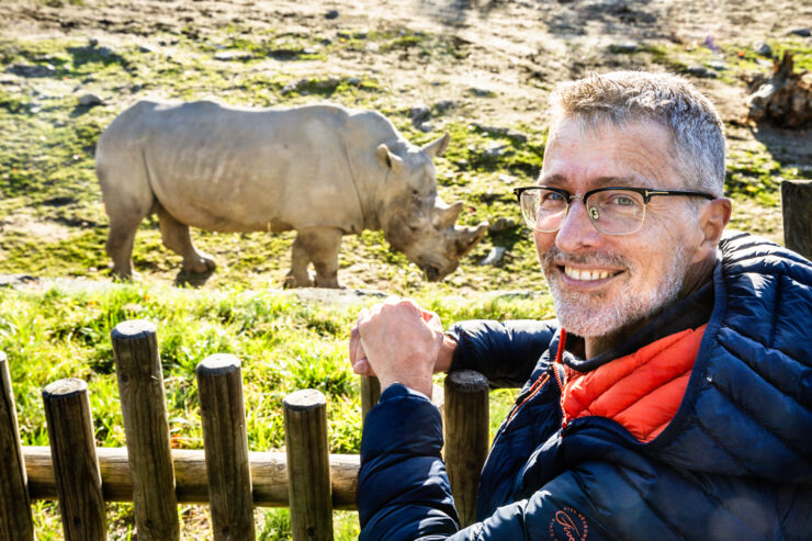 Man (Fredrik Gustafsson) vid staket med noshörning i bakgrunden