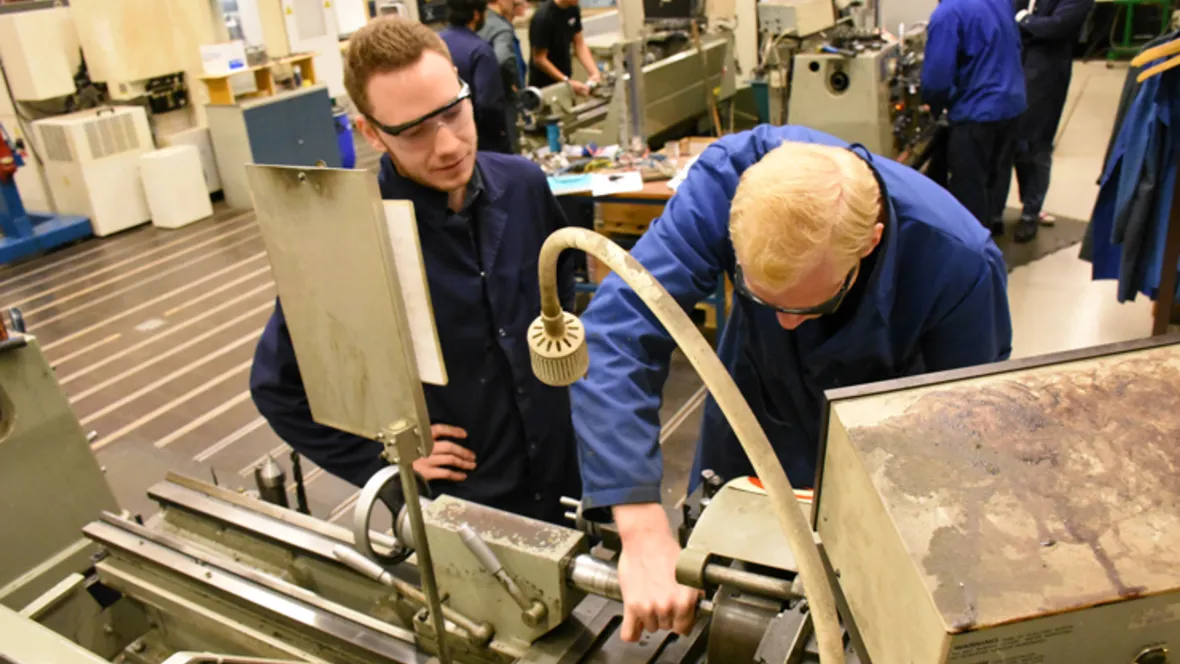 Två ingenjörsstudenter lär sig svarva i metall för bättre förstå processen vid metallbearbetning.