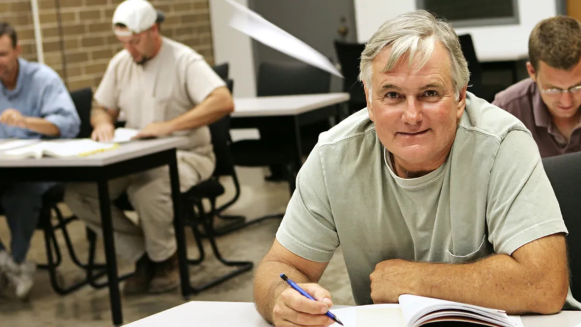 An man sitting on a school bench.