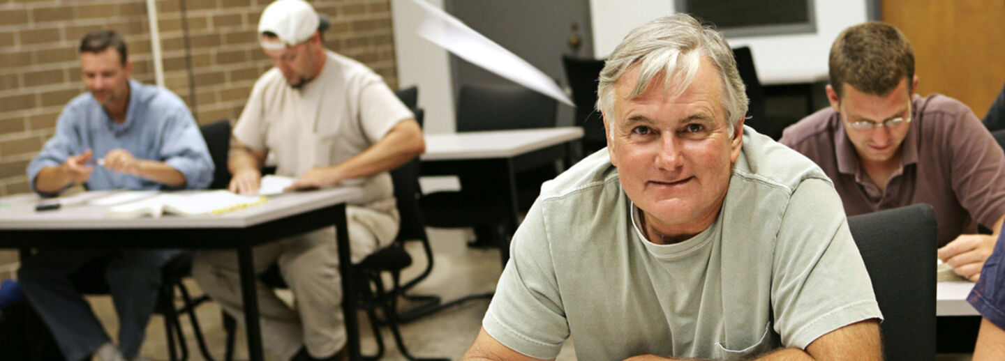 En man sitter i en skolbänk. 