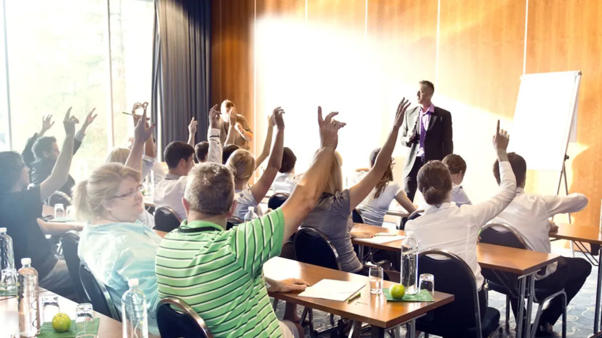 A room full of people raising their hands.