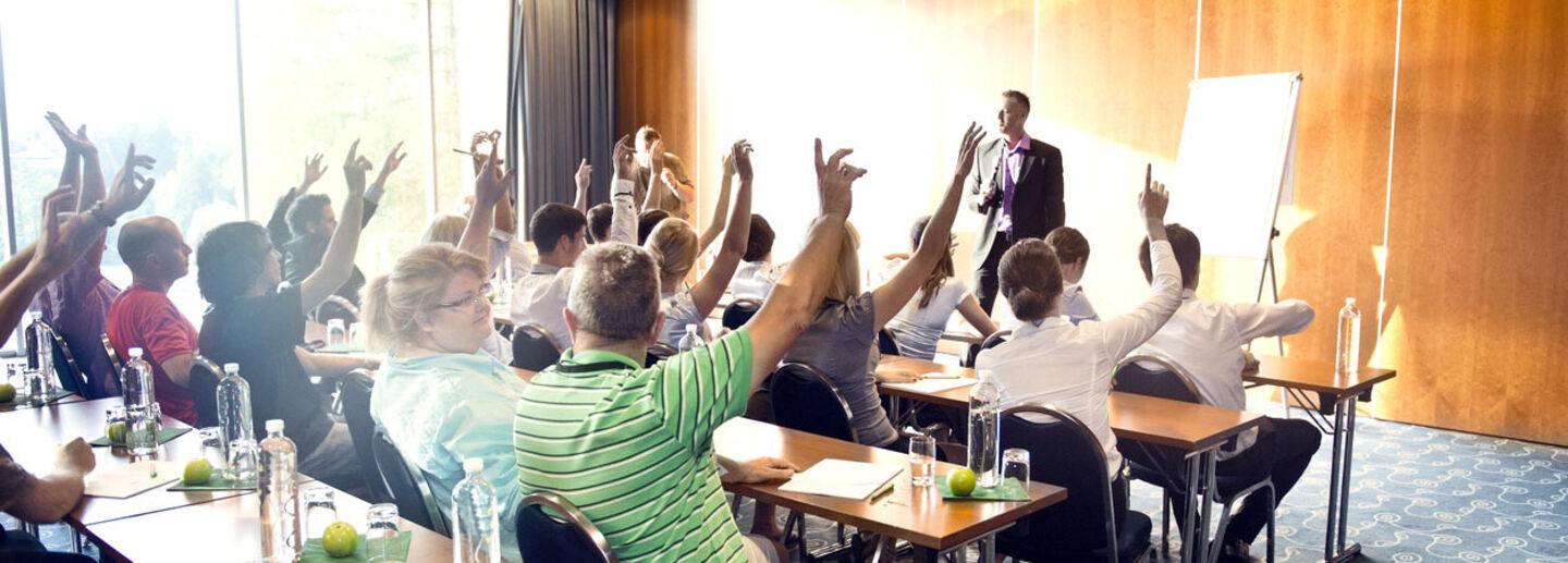 A room full of people raising their hands.