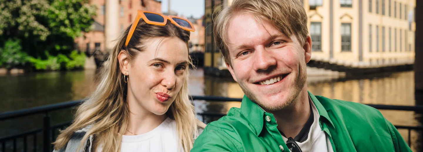 A female and a male student outdoors look into the camera
