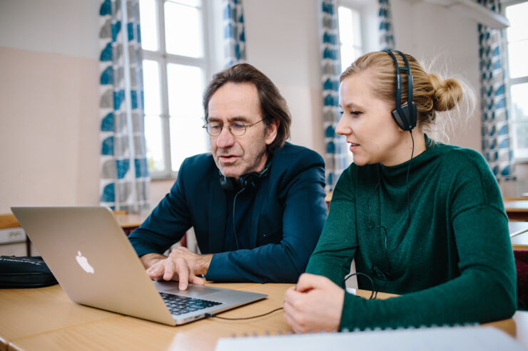 A man and a woman sit in front of a computer