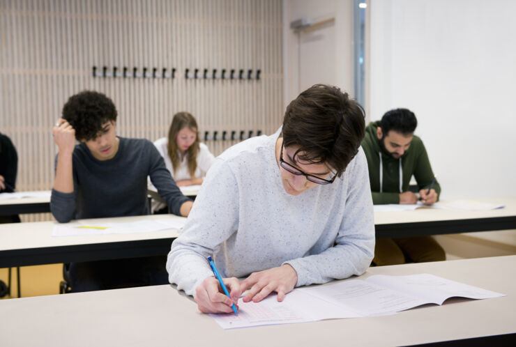 Personer skriver högskoleprovet i skrivsal