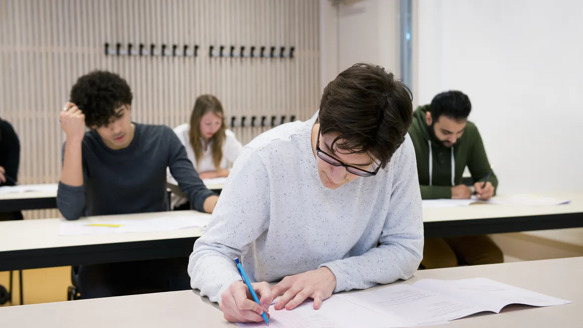 Personer skriver högskoleprovet i skrivsal