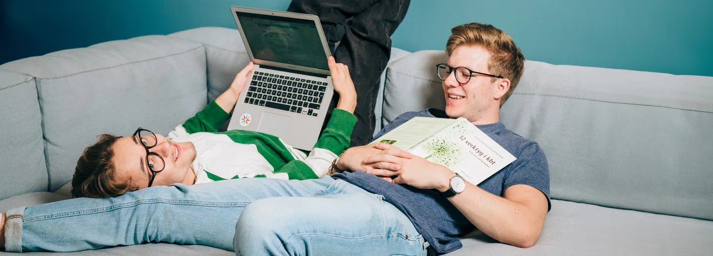 Två studenter sitter på en soffa och pluggar