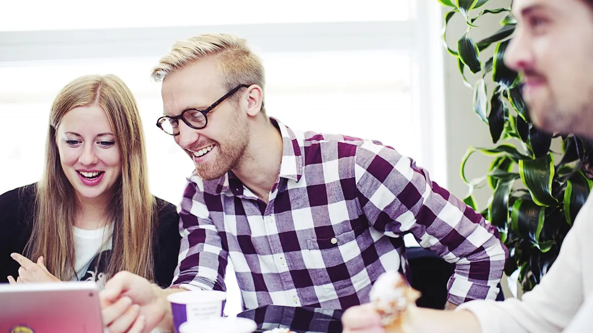 Kvinna med långt hår och man i rutig skjorta tittar på laptopskärm