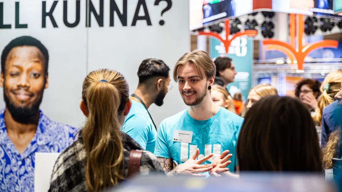 LiU-student med turkos t-shirt pratar med besökare på mässa