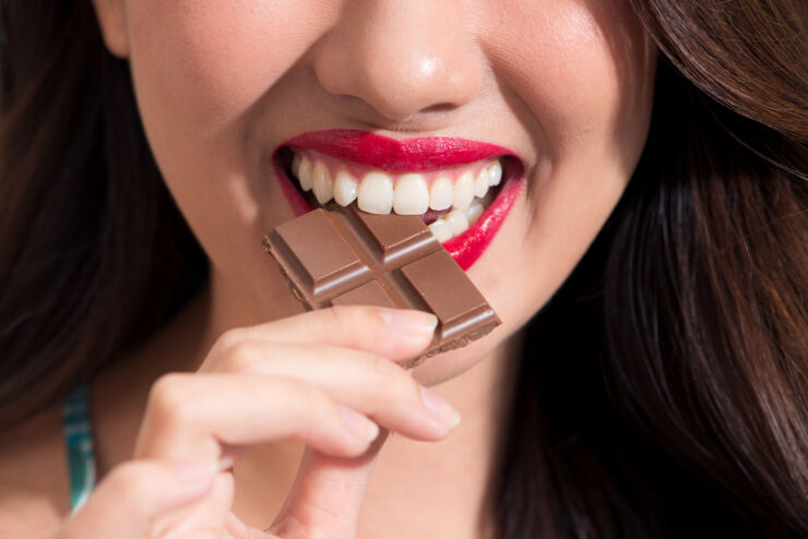 Woman eating av piece of chocolate.