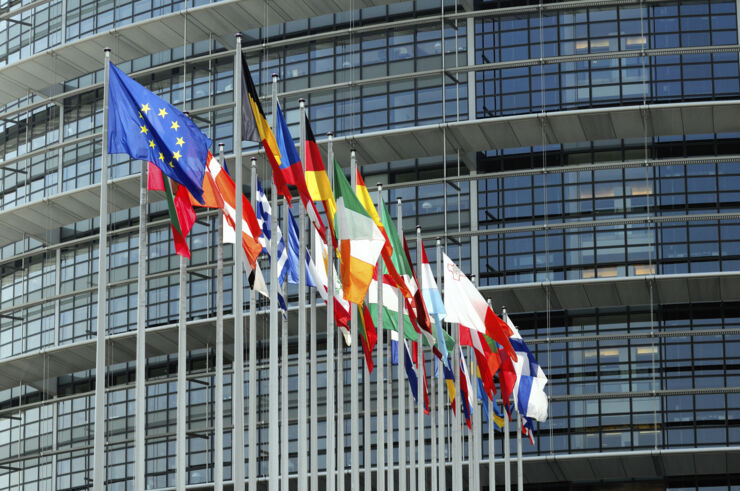 Flagpoles with flags and a building in the background