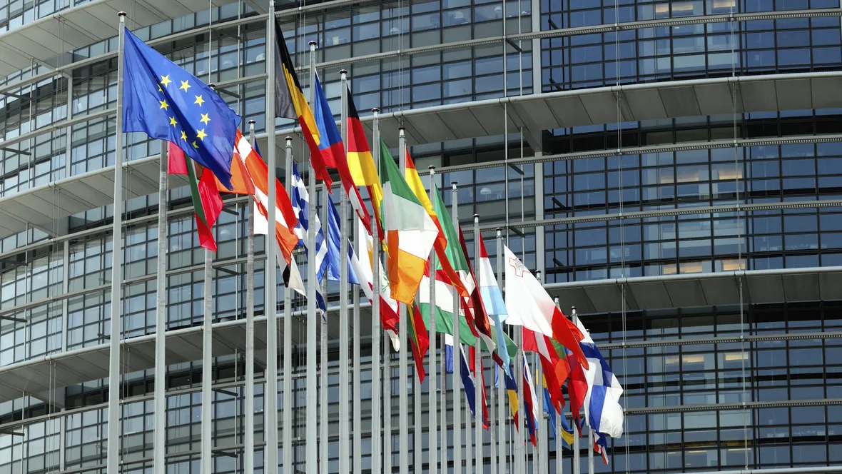 Flagpoles with flags and a building in the background