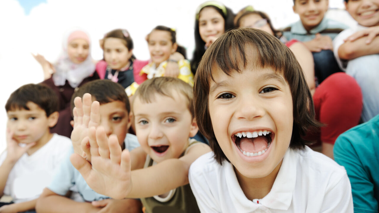 Närbild på en grupp glada barn. Himmel i bakgrunden