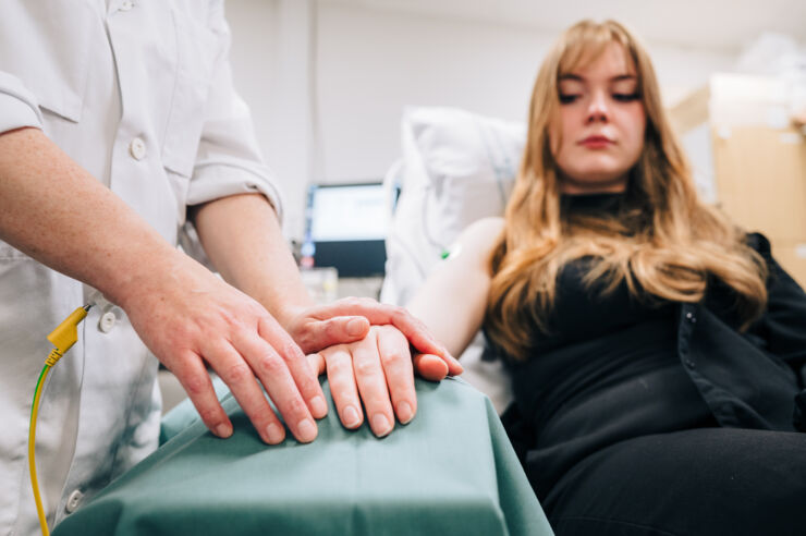 Researcher touches the arm of a young woman in a lab environment.