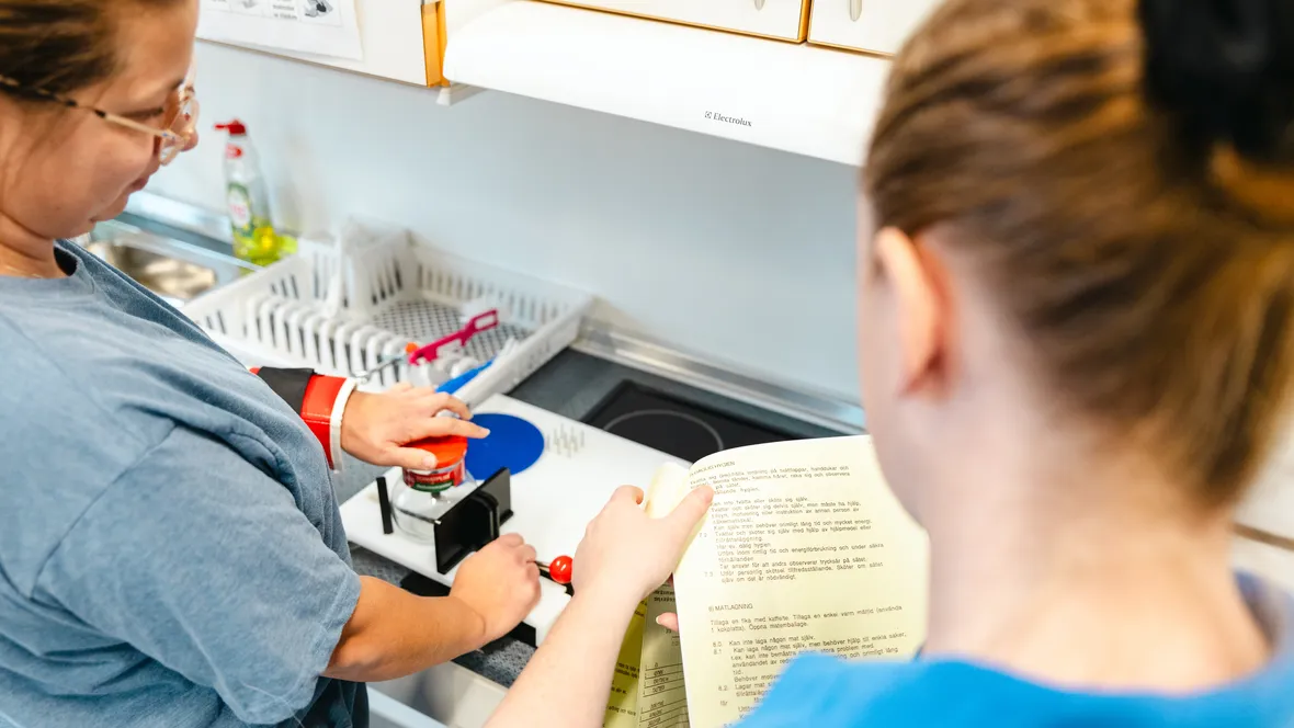 En kvinna använder ett hjälpmedel för att öppna en glasburk med skruvlock medan en arbetsterapeut observerar..