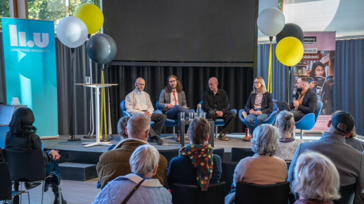 En grupp personer sitter i panel och samtalar.