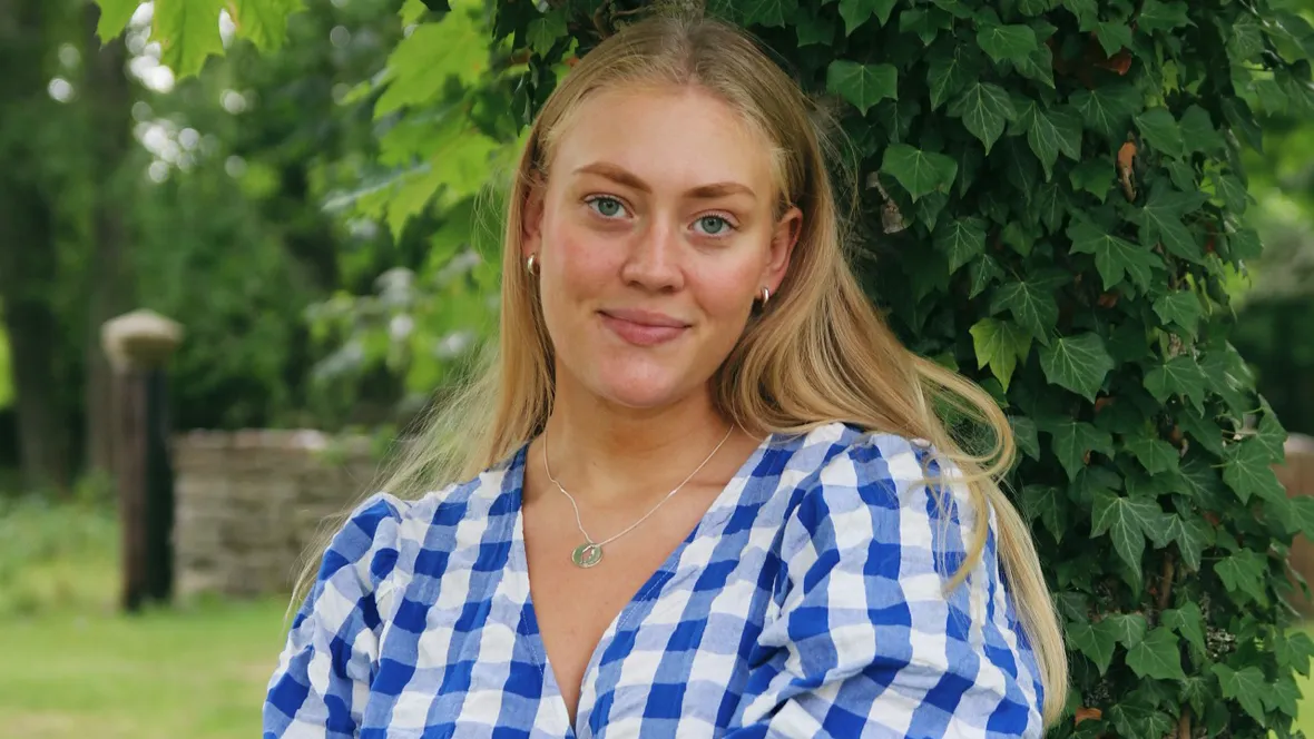 Ung blond kvinna med blå- och vitrutig blus