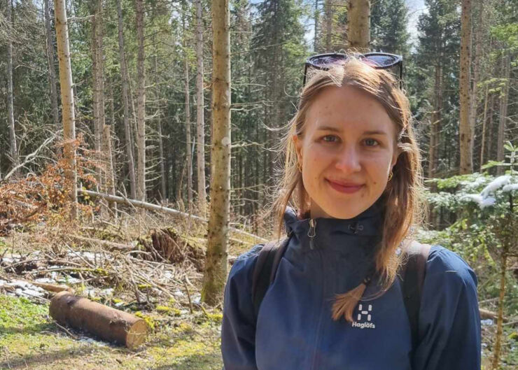 Ung kvinna med långt hår framför en skog