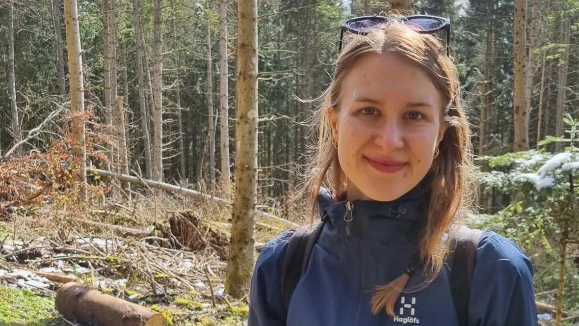 Ung kvinna med långt hår framför en skog