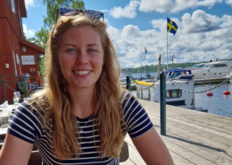 Young blonde woman in a striped t-shirt. A Swedish flag in the background