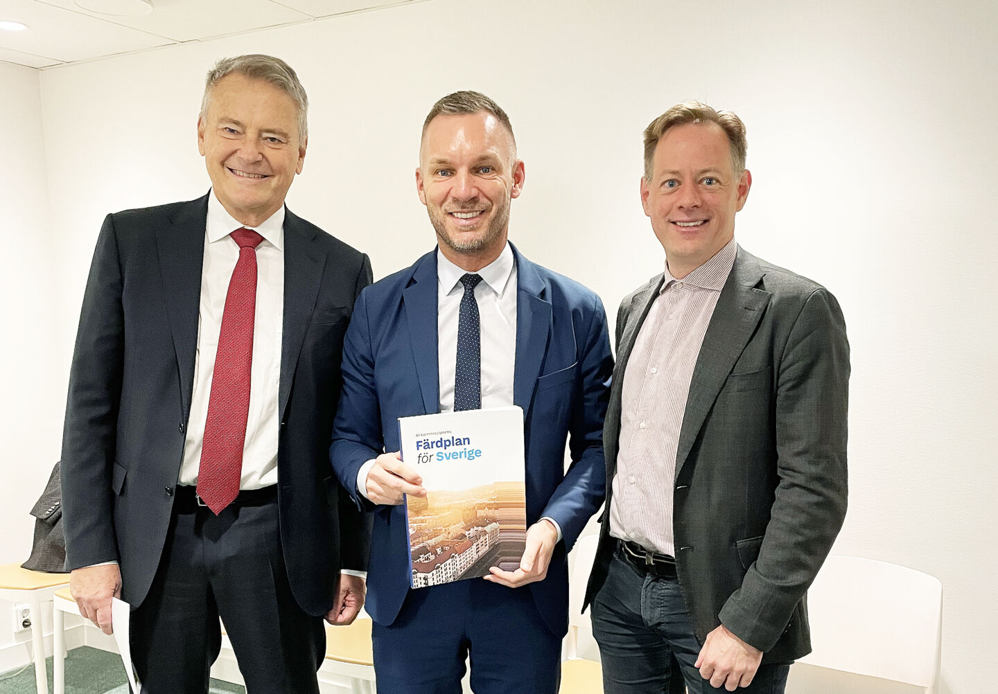 Tre män och en rapport i handen på den mittersta