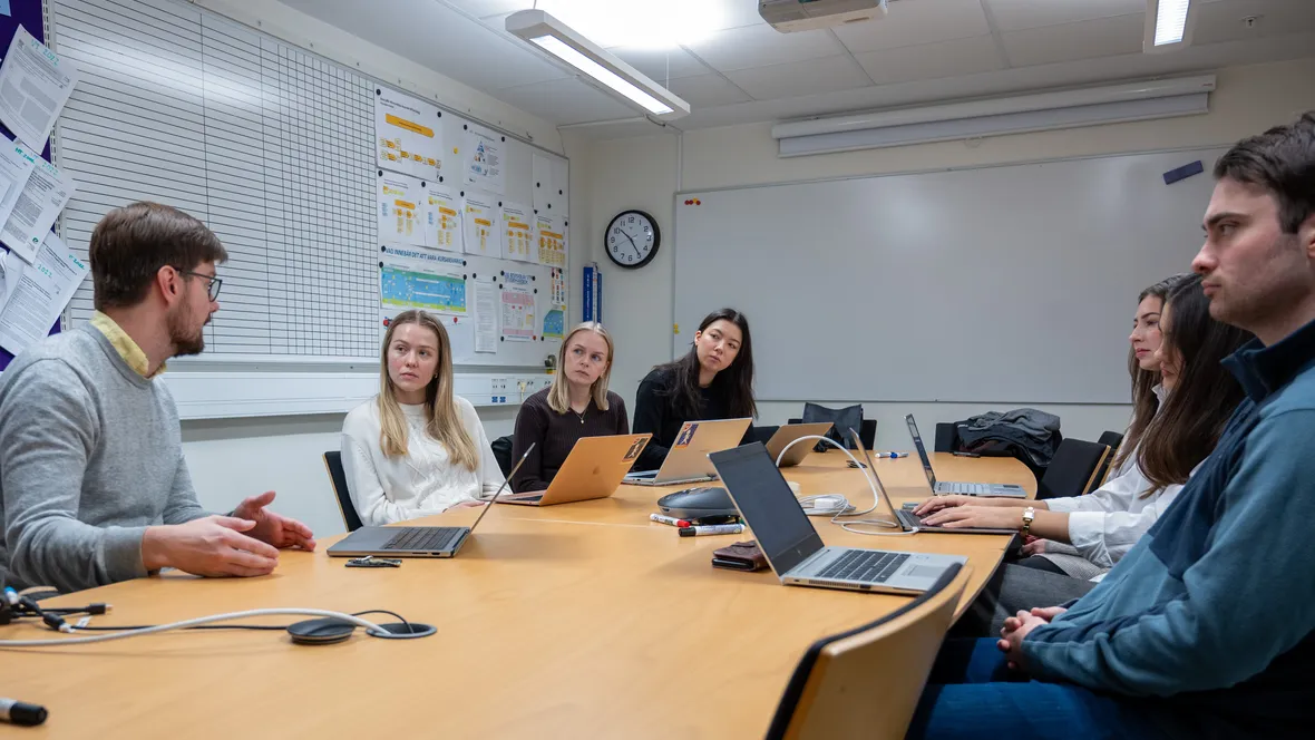 A diverse group of individuals collaborates around a table, each engaged with their laptops in a productive setting.
