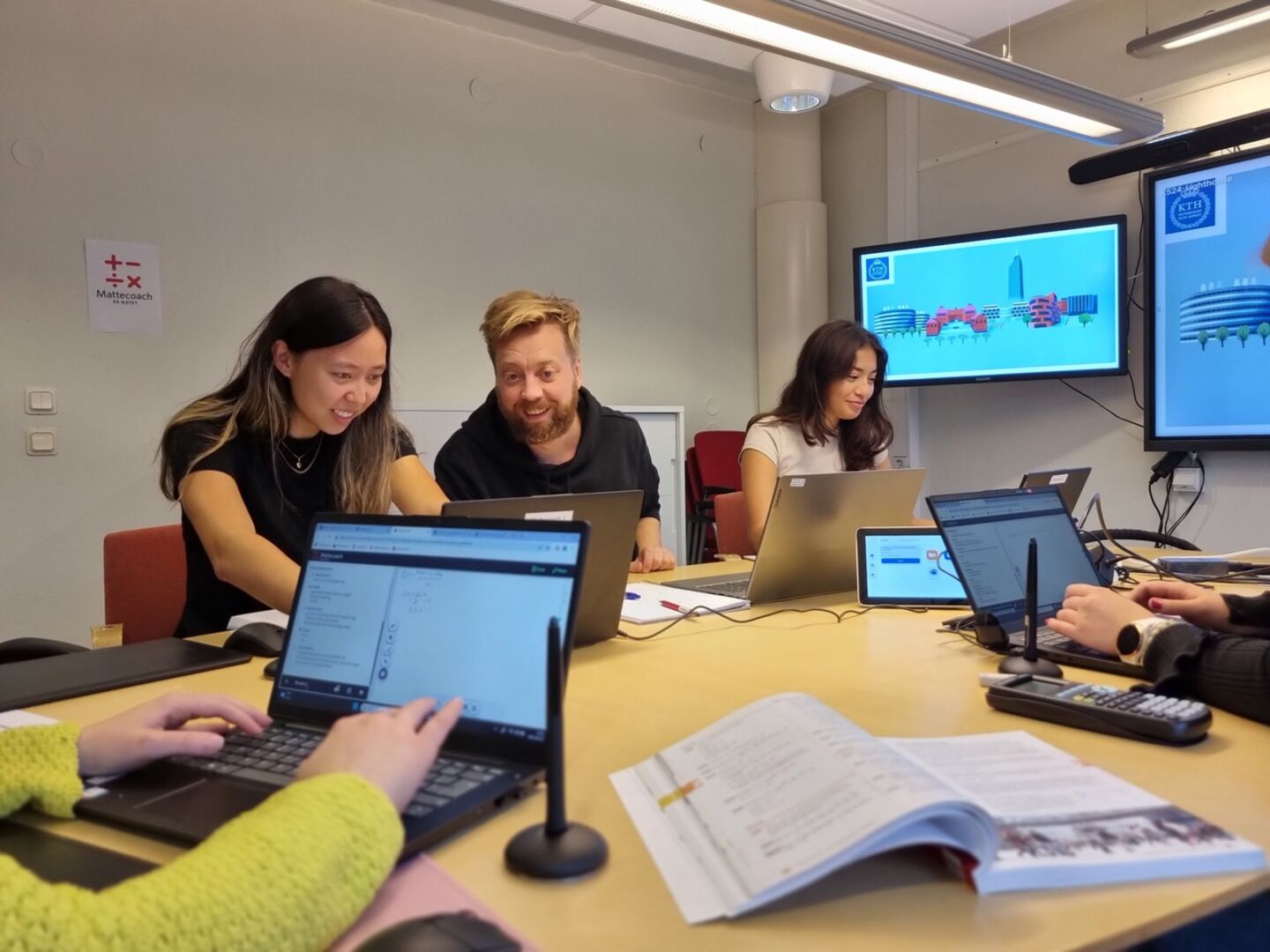 Young people look happy and work with computers with math books next to them