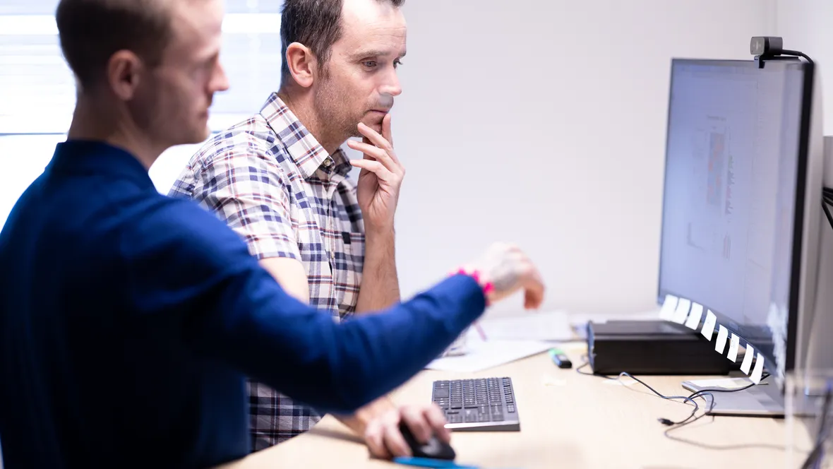 Två män tittar på forskningsdata på en datorskärm. 